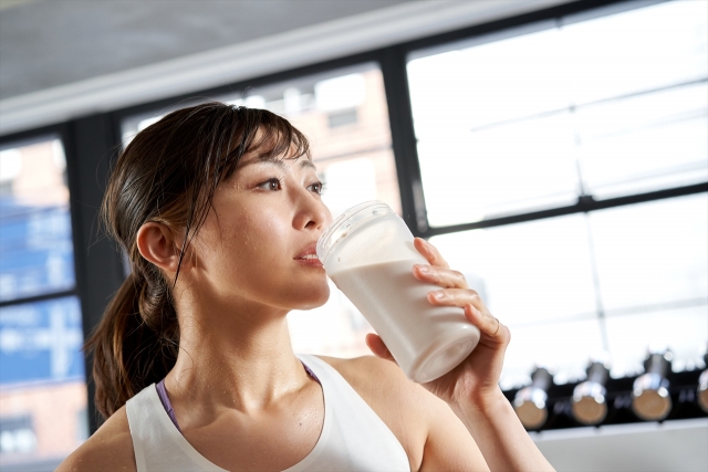 トレーニング後に、プロテインドリンクを飲む女性