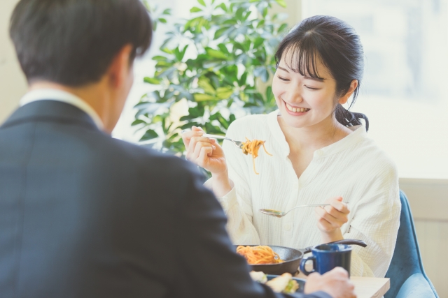 ランチタイムにパスタを食べるカップルの女性