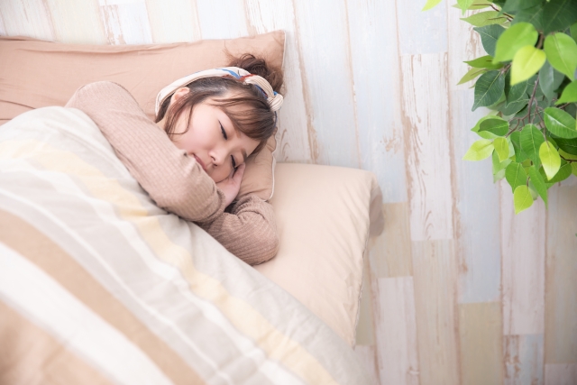 ベッドで横向きになって眠る女性